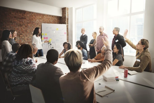 People in a meeting room around a table talking
