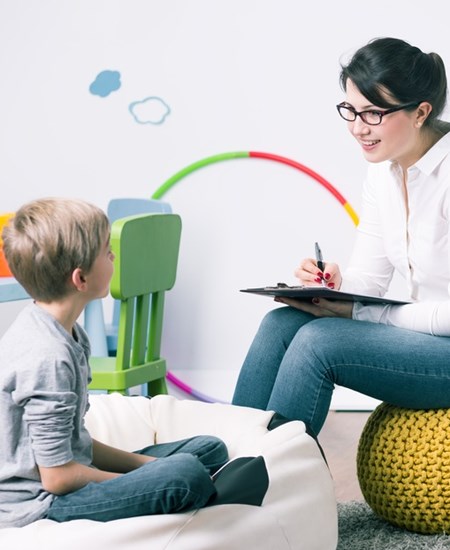 Woman sitting in front of a child with a clip board