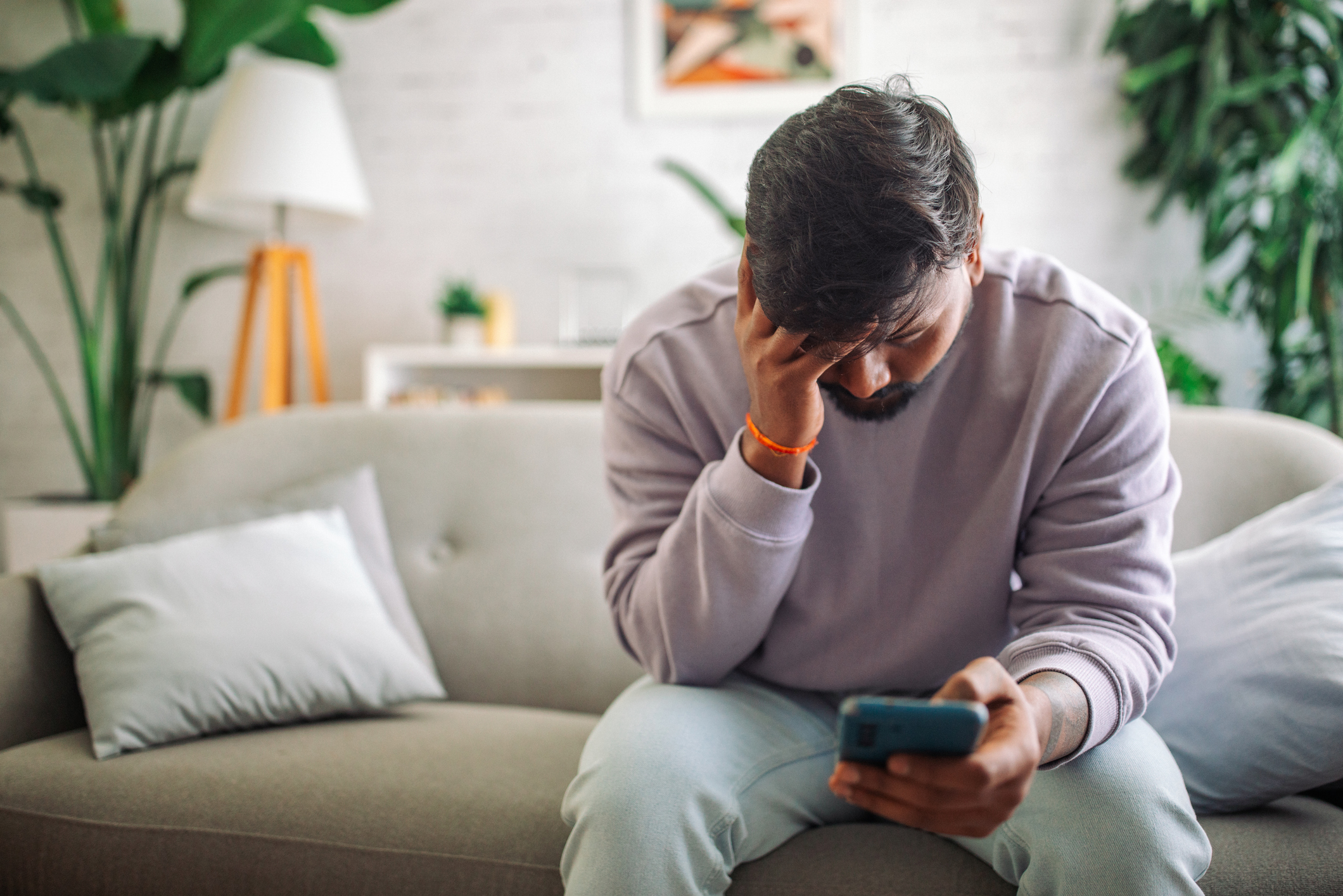 Upset young man with head in hand looking at cell phone 