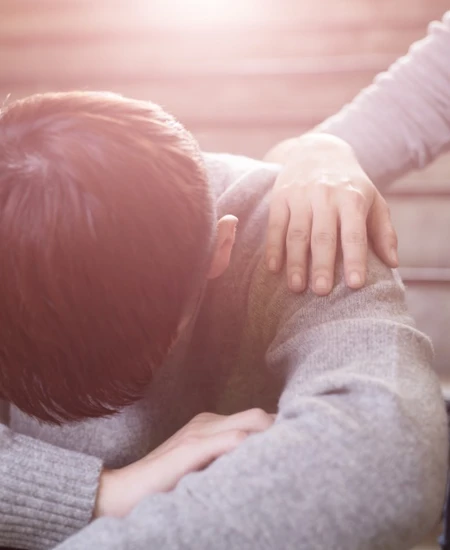 Boy with head on his knees and a girls hand on his shoulder