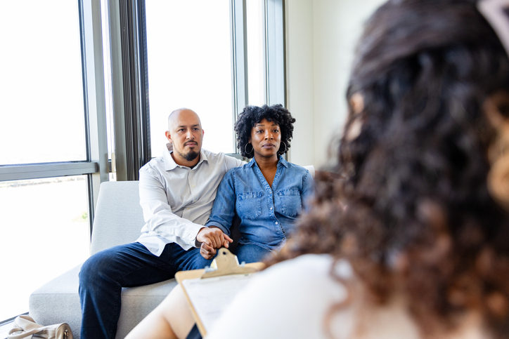 Serious couple in marriage counseling session with therapist. 