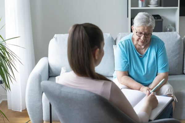 Serious senior woman talking with counselor in her home