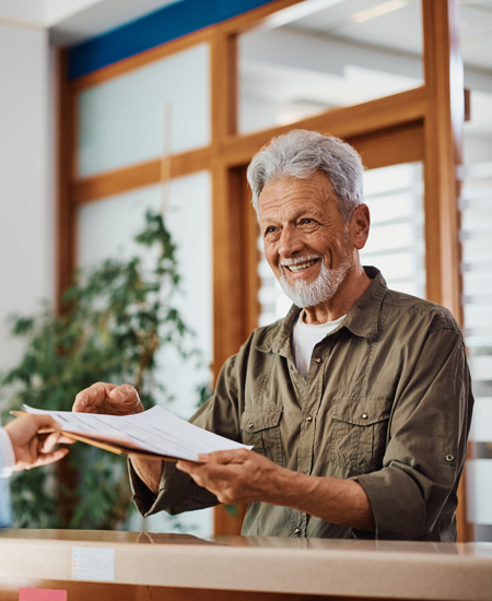 happy senior man gives paperwork to front desk