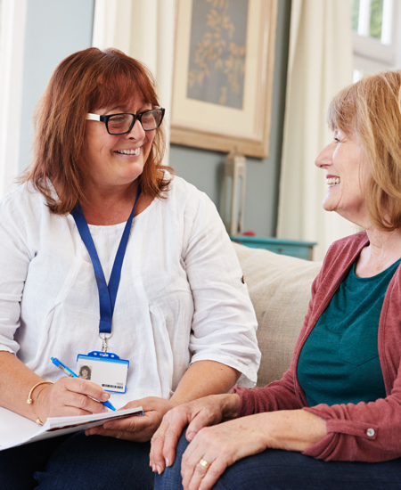 Two women sitting on a couch smiling 