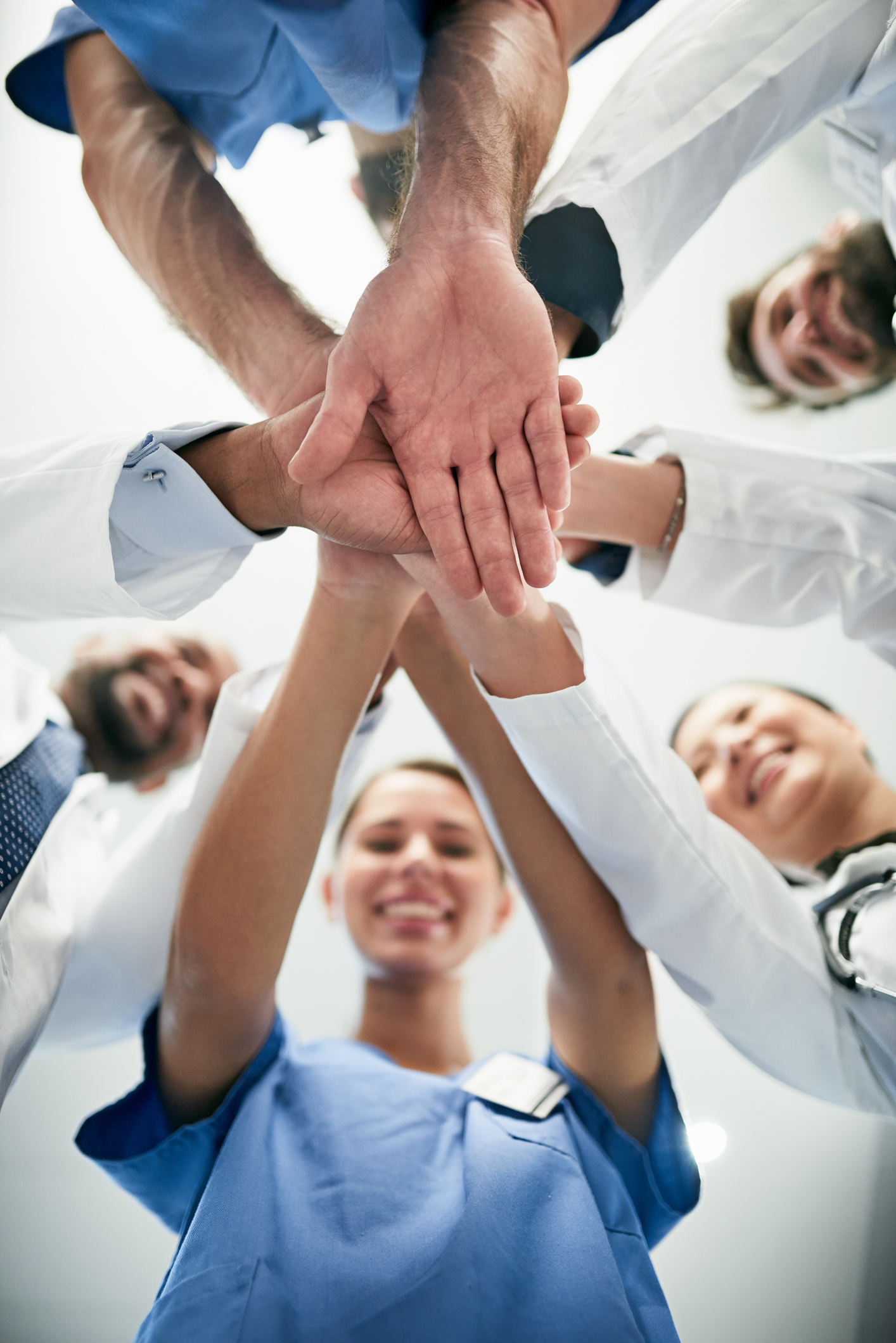 Shot of a diverse team of doctors joining their hands together in unity