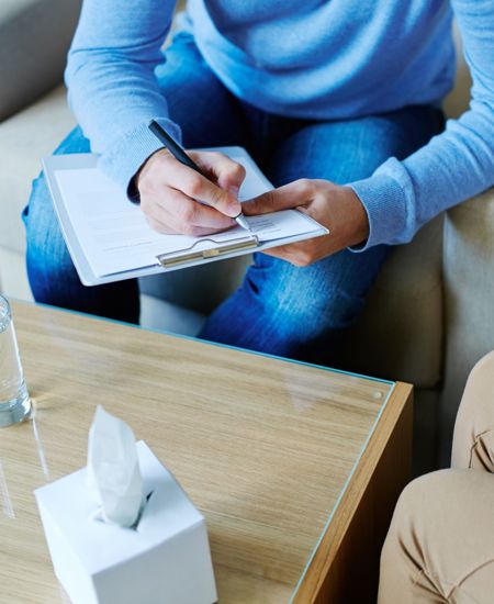 counselor writing on clip board in front of patient  
