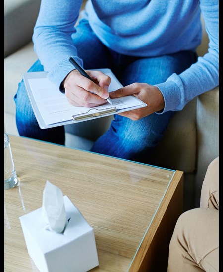 counselor writing on clip board in front of patient