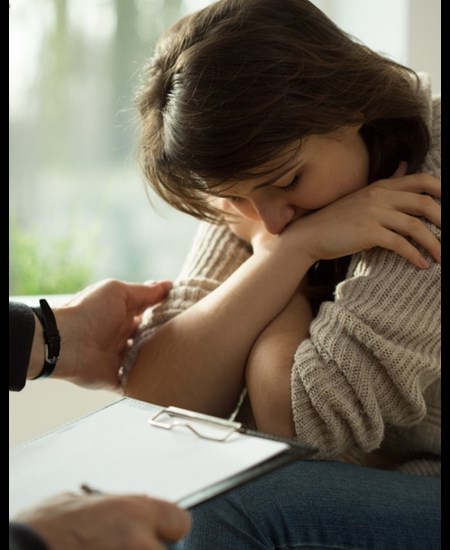 Girl with arms crossed, therapist in front of her