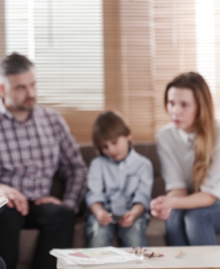 Mom, dad, child all sitting together talking to a counselor 